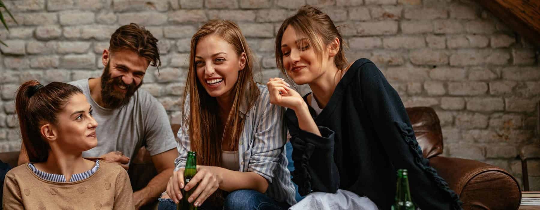 residents laugh and talk on leather couch